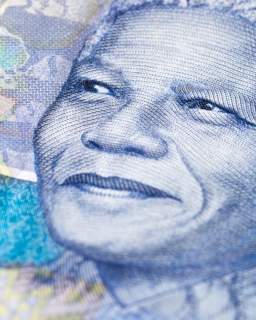 A close-up of a detail of a South African Hundred Rand banknote, featuring an engraving of the face of iconic statesman Nelson Mandela, giving his trademark smile. South African wildlife and African designs form the watermarked background. Photo: Istockphoto. Copyright. 