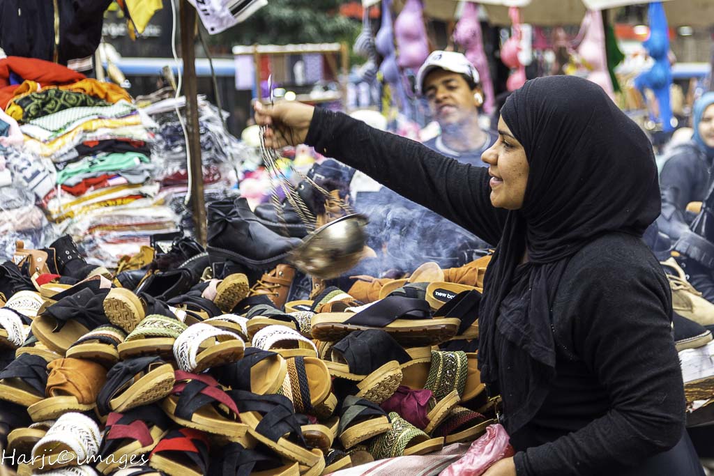 A woman exorcising evil spirits from a shoe stand with “Loban” (incense). Photograph: © Muslim Harji. 