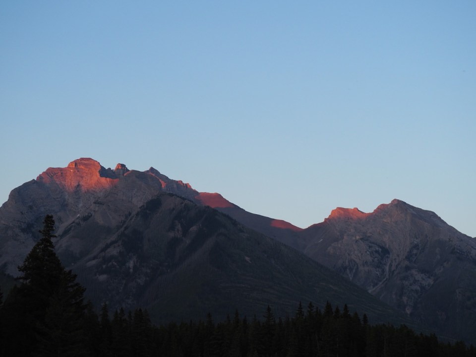 Setting sun casts a glow on mountain peaks, Johnson Lake, Minnewanka Loop, Banff National Park, Alberta, Canada, July 2026. Photograph: Malik Merchant / Simergphotos.